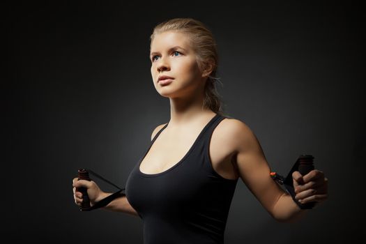 Woman exercising with a resistance band on dark background