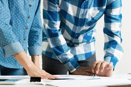 Professional designers discussing architecture project. Creative teamwork and project brainstorming. Close up human hands and construction drawing of building on desk. Industrial engineering company.