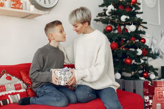 Beautiful mother in a white sweater. Family in a christmas decorations. Little boy in a room