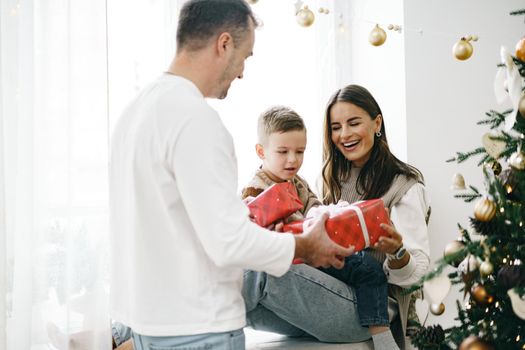 Smiling parents giving Christmas present to son at home, portrait