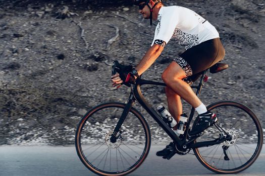 Professional man cyclist on a mountain road at sunrise