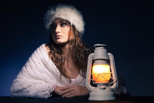 portrait of beautiful woman sitting with lantern over dark background