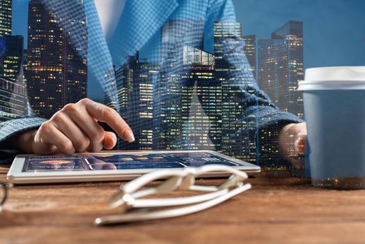 Businesswoman using tablet computer at wooden desk. Close up woman hand pointing on touchscreen. Business application with online financial analytics on screen of tablet device. Strategy planning