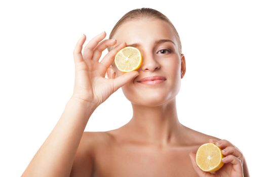 young woman holding lemon slice in front of eye over white background