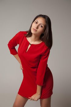 Young girl in a red dress on gray background