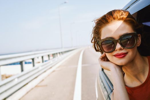 cheerful woman peeking out of the car window trip adventure lifestyle. High quality photo