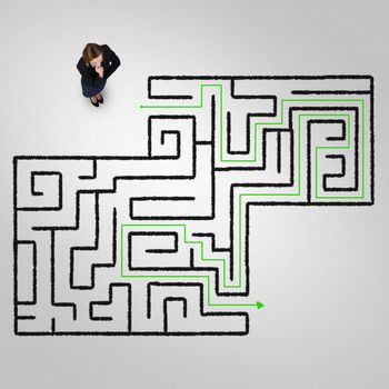 Top view of puzzled businesswoman looking at drawn maze on floor