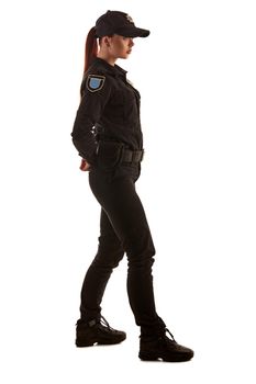 Full length shot of a serious redheaded woman police officer in a uniform and a cap posing sideways for the camera, isolated on white background. Defender of citizens is ready to enforce a law and stop a crime.