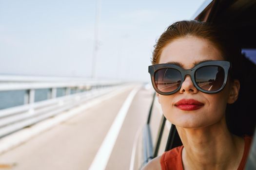 cheerful woman peeking out of the car window trip adventure lifestyle. High quality photo