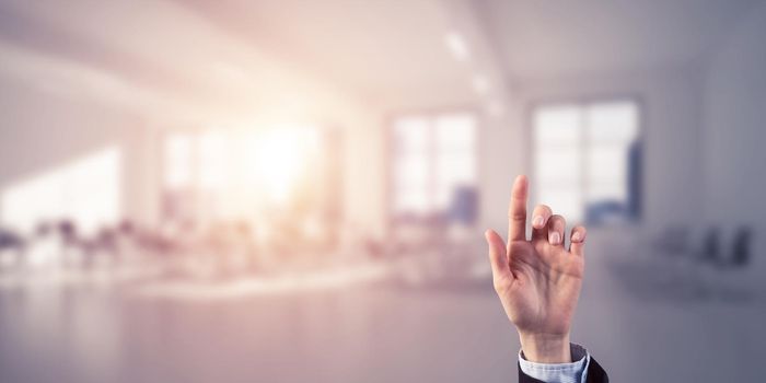 Close of businesswoman hand touching screen with finger and office at background