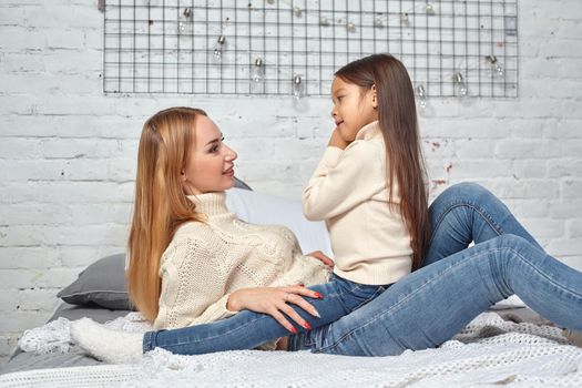 Happy loving family. Mother and her daughter child girl playing and hugging on bed