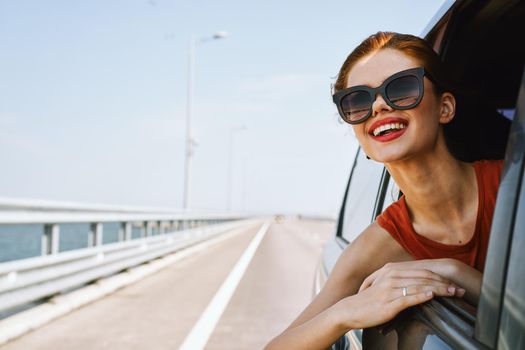 a woman is driving in a car on the road and looking out of the window. High quality photo