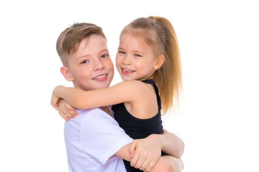 Charming little girl hugging a tall boy with blond hair. A romantic couple is happy with the joint time brought. A happy sister hugs her brother. The concept is a happy childhood. Isolated on white background.