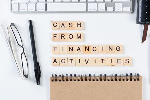 Cash from financing activities concept with letters. Still life of office workplace with supplies. Flat lay white surface with computer keyboard and notepad. Financial management and accounting.