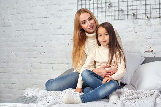 Happy loving family. Mother and her daughter child girl playing and hugging on bed