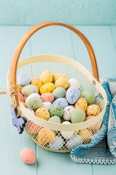 Metal basket with colourful Easter quail eggs. Spring holidays concept with copy space.