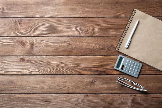 Still life of accountant vintage workspace with office accessories. Flat lay old hardwood desk with notepad, pen and calculator. Accounting and banking services. Finance and investment concept.