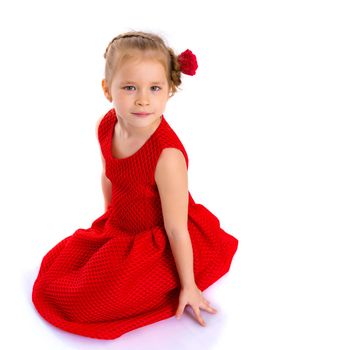 Beautiful little girl is sitting on the floor in the studio. The concept of a happy childhood, beauty and fashion. Isolated on white background.