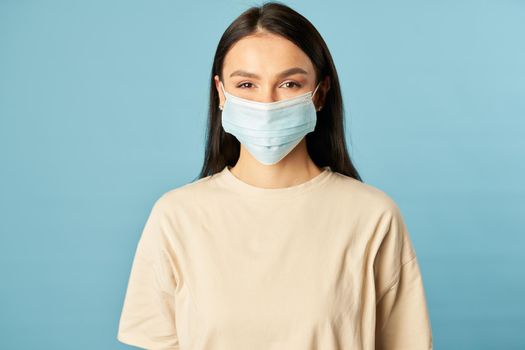 Waist up of pretty young lady posing and looking at camera while wearing protective face mask. Quarantine, coronavirus concept. Copy space