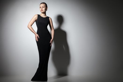 beautiful woman model posing in elegant black dress in the studio