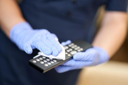 Close up of maid wearing protective gloves when cleaning the console in hotel room. Hotel service concept