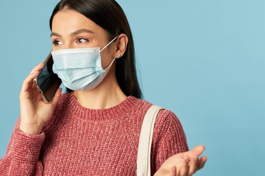 Beautiful brunette in protective mask talking on the mobile phone while shopping. Copy space. Quarantine, coronavirus concept