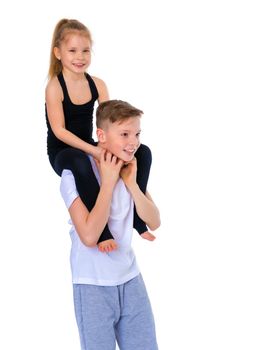 Charming little girl hugging a tall boy with blond hair. A romantic couple is happy with the joint time brought. A happy sister hugs her brother. The concept is a happy childhood. Isolated on white background.