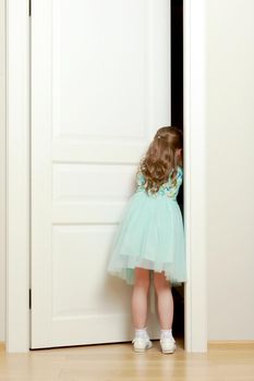 A nice little girl is standing by the door. The concept of family happiness and a home.