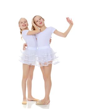 2 cheerful girls twins in white gymnastic costumes posing for the camera.Isolated on white background.