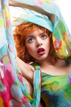 Girl with beautiful red hair and colorful dress and fabric over white background
