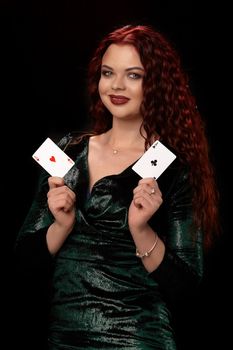 Sexy redheaded woman whith a curly hair is posing with a playing cards in her hands, on black background Win casino holdem poker slots