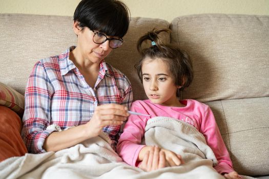 Mother measuring her daughter's temperature with a digital thermometer to check for fever