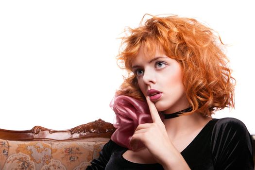 Girl with beautiful red hair, pink bow and black dress making a hush gesture over white background