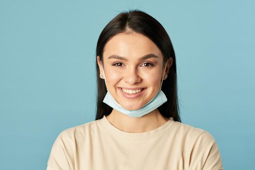 Waist up of happy young woman posing and looking at camera while wearing protective face mask. Quarantine, coronavirus concept. Copy space