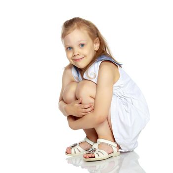 Little girl is sitting on the floor. The concept of a happy childhood. Isolated on white background.