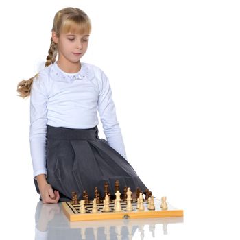 A little girl is playing chess. The concept of creative education of a child, training of thinking. Isolated on white background