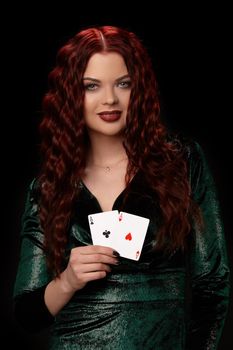 Sexy redheaded woman whith a curly hair posing with playing cards in her hands and looking at the camera, on black background Win casino poker slots