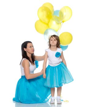 Beautiful mother and daughter in long blue skirts, along with balloons.Isolated on white background.