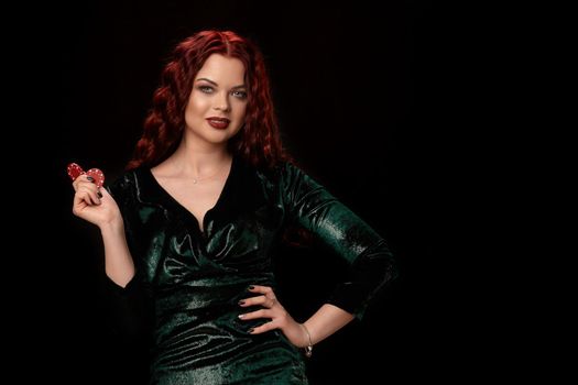 Beautiful redheaded woman whith a curly hair posing with chips in her hands and smiling, on black background Win casino holdem poker slots