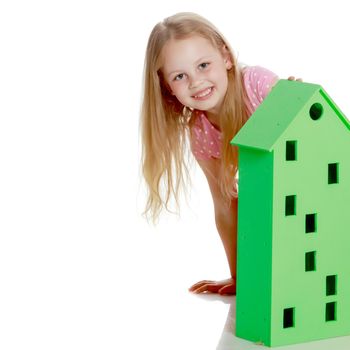 A cute little girl is playing with wooden houses. The concept of family happiness, play, creative development of the child.