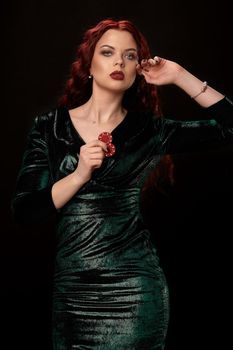 Beautiful redheaded woman in a black leather dress is touching her face, over black. Win casino holdem poker slots