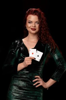 Sexy redheaded woman whith a curly hair posing with a playing cards in her hands, on black background Win casino holdem poker slots