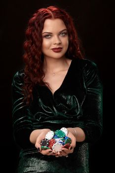 Beautiful and sexy redheaded woman with a lot of chips in her hands, over black. Win casino holdem poker slots