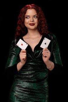 Charming redheaded woman whith a curly hair posing with a playing cards in her hands and smiling, on black background Win casino holdem poker slots