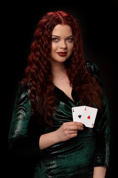 Sexy redheaded woman whith a curly hair and red lipstick on her lips, smiling with a playing cards in her hands, on black background Win casino poker slots