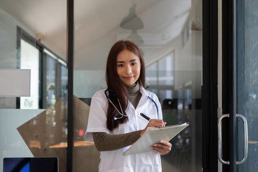Portrait Of Smiling Asian Female Doctor With Stethoscope and checking list on clipboard.