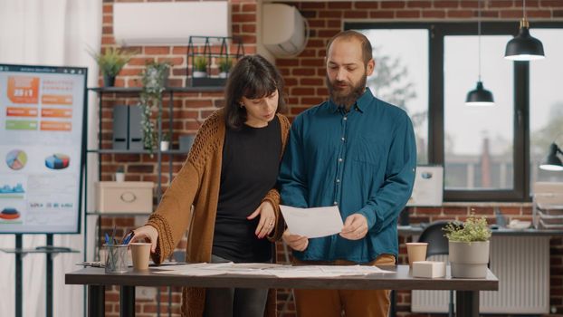 Workmates shaking hands and preparing to work on business at office. Man and woman greeting with handshake and doing teamwork to design rate charts. Colleagues working on project planning