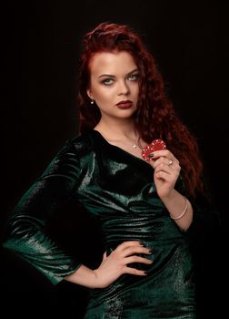 Young redheaded woman whith a languishing look, curly hair and chips in her hands, over black. Win casino holdem poker slots
