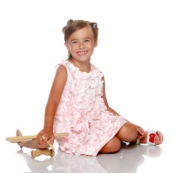 Little girl is sitting on the floor. The concept of a happy childhood. Isolated on white background.