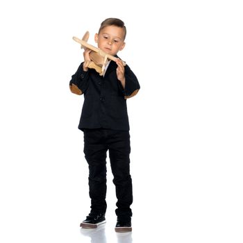 Happy kid boy plays with wooden toy airplane.Isolated on white background.